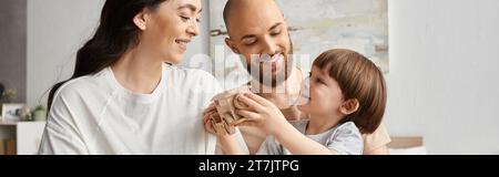 Glückliche moderne Eltern lächeln fröhlich, während sie mit ihrem kleinen Sohn spielen, Familienkonzept, Banner Stockfoto