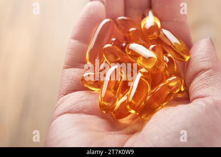 Frau oder Arzt hält Kapseln mit Vitamin D, E oder Omega-3,6,9-Fettsäuren in der Hand. Nahrungsergänzungsmittel mit Öl gefülltem Fischöl. Natürliche Nahrungsergänzungsmittel für ihn Stockfoto