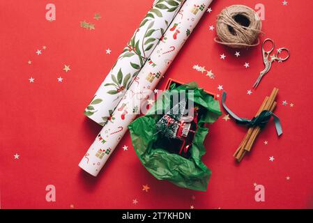 Die Rollen Geschenkpapier mit Garn und Schere auf roter Oberfläche Stockfoto