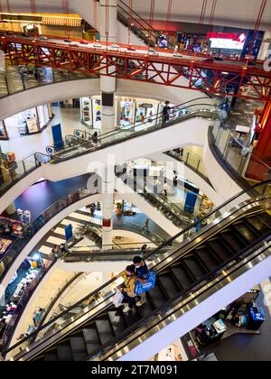 Im modernen Pier 21 Shopping Center in Bangkok, Thailand, fahren die Menschen mit den Rolltreppen neben einem Modell der Golden Gate Bridge. Stockfoto