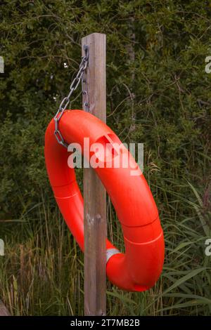 Rote Rettungsring-Boje hängt an einem Holzmast, Nahaufnahme Stockfoto