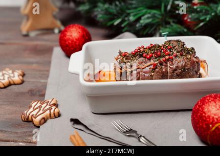 Tisch mit Weihnachtsgeschirr. Gebackenes oder geröstetes Rindfleisch mit Gewürzen, zartes Fleisch. Tischeinstellung. Weihnachtsessen mit der Familie. Stockfoto