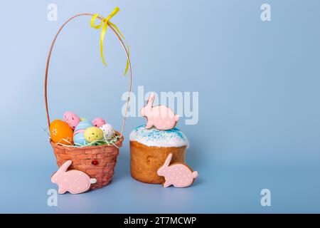 Niedlicher rosafarbener Lebkuchen in Form eines Kaninchens , Osterkuchen und ein Korb mit bunten Eiern Stockfoto
