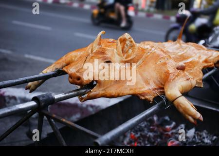 Knuspriges Schwein, gegrillt auf Spieß, traditionelle Kohle und Feuer. Ein ganzes Schwein, das auf offenem Feuer gebraten wurde. Asiatisches oder orientalisches Streetfood oder festliches Essen Stockfoto