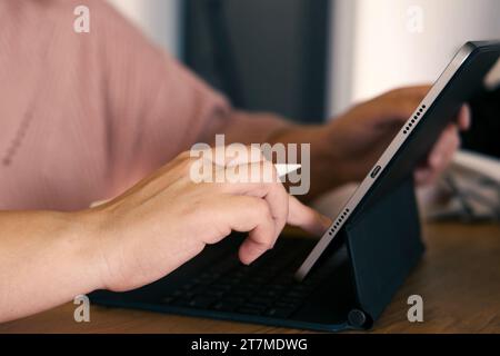 Unerkennbare Frauenhand mit einem Grafiktablett-Computer mit Stift-Stift in einem Café. Zugeschnittene Aufnahme einer Frau, die auf einem digitalen Touchscreen arbeitet DE Stockfoto