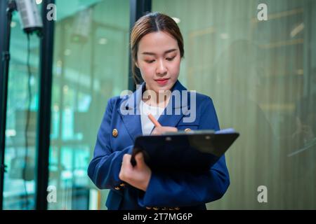 Porträt einer jungen asiatischen Geschäftsfrau, die auf dem Klemmbrett schreibt. Im modernen Büro. Business Success-Konzept. Stockfoto