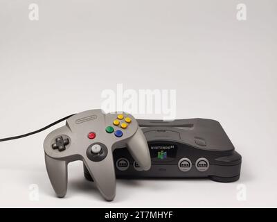 Eine graue Nintendo 64 Retro-Konsole mit einem grauen Joypad ist auf weißem Hintergrund abgebildet Stockfoto
