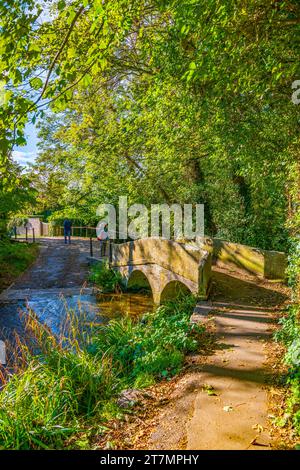 Der Bide Brook ford und die Fußgängerbrücke auf dem Nethercote Hill in Lacock Village, Wiltshire, England, Großbritannien Stockfoto