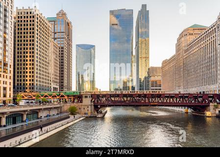 Hochzug überquert den Chicago River, gesäumt von Wolkenkratzern bei Sonnenuntergang Stockfoto