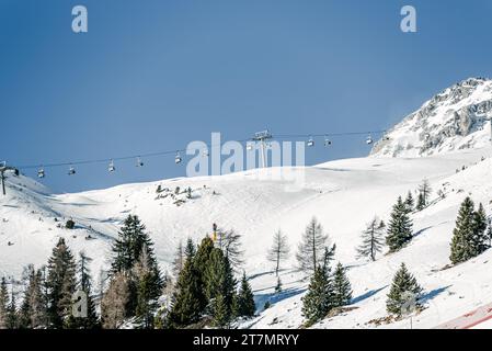 Charilift über eine Skipiste in den Alpen an einem klaren Wintertag Stockfoto