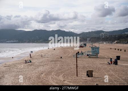 Santa Monica, Kalifornien, USA - 5. Mai 2023: Bewölkter Sonnenuntergang auf Santa Monica mit einem Rettungsschirm und Menschen, die am Strand spazieren gehen Stockfoto