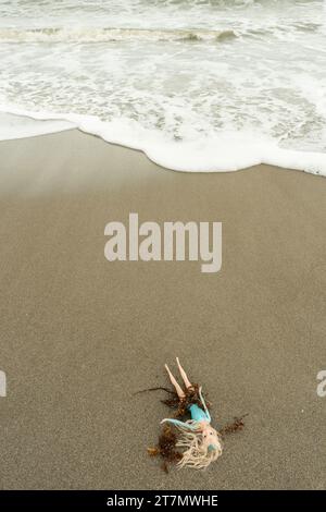 Eine weibliche Spielzeugpuppe mit langen blonden Haaren wird am Strand im Atlantik, Cocoa Beach, Florida, USA, gespült Stockfoto