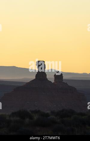 Dämmerungslicht mit Hinterleuchtung des Rooster Butte, links, und des Setting Hen Butte im Valley of the Gods, Bears Ears National Monument, Utah. Stockfoto