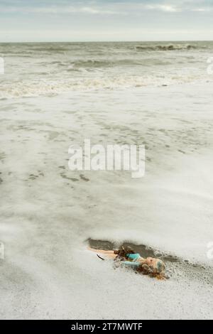 Eine weibliche Spielzeugpuppe mit langen blonden Haaren wird am Strand im Atlantik, Cocoa Beach, Florida, USA, gespült Stockfoto