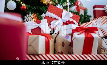 Ordentlich verpackte Geschenkboxen unter dem modernen Weihnachtsbaum in einem Haus, ergänzt durch Weihnachtsschmuck, eine festliche Neujahrsdekoration. Stockfoto