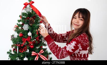 Asiatische Frau, die weihnachtsbaum mit modernem Element im Wohnzimmerhaus dekoriert. Frohe weihnachten und ein frohes neues Jahr. Mädchen, das Weihnachtsschmuck macht Stockfoto