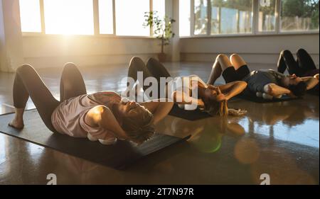 Yoga-Teilnehmer in einer Ruheposition auf Matten mit Massageball in einem sonnendurchfluteten Studio Stockfoto