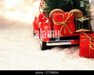 Red christmas Truck mit Weihnachtsbäumen und Geschenkboxen im Schnee, selektiver Fokus auf den Vordergrund, Platz für Ihren Text auf der rechten Seite Stockfoto