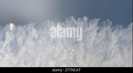 Nahaufnahme von Eis und Schneekristallen, die im weichen, hellen Licht leuchten. Der Hintergrund ist hell und es gibt Platz für Text. Stockfoto