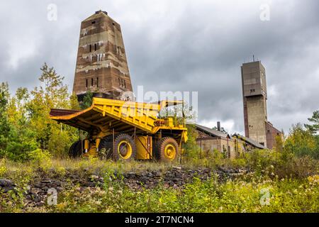 Nur die Reifen des Erztransporters vor den Ishpeming-Wickeltürmen sind 4 Meter hoch. Es wurde für den Transport von 170 Tonnen Erz genutzt. Im Hintergrund wurde die „A-Schacht“-Mine, die 1967 stillgelegt wurde, vom Architekten George Washington Maher in Form eines Obelisken entworfen und der modernere Koepe-Hebezug aus dem Jahr 1955 gebaut. Stille Zeugen des Eisenbergbaus in Ishpeming, Michigan, USA Stockfoto