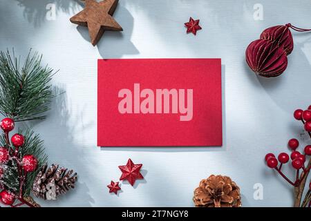 Weihnachtliche flache Lagenkomposition mit rotem Dekor. Brief an den Weihnachtsmann und Weihnachtsbaumzweig auf blauem Hintergrund Stockfoto