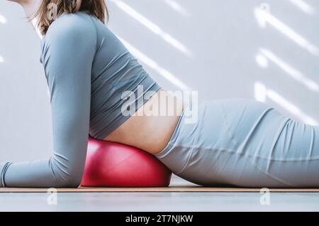 Frau, die Zwerchfellatmungs-Übungen mit weichem Pilates-Ball macht Stockfoto