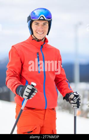 Junge Skifahrer, die auf den Pisten in einem Bergskigebiet stehen. Mann posiert draußen an einem sonnigen Wintertag. Stockfoto