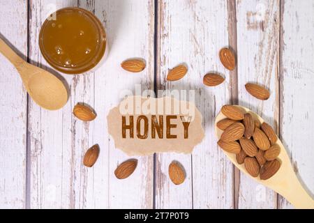 Honig gemischt mit Nüssen, die aus einem Holzlöffel in einem Honigglas fließen. Hintergrund mit Holzstruktur. Nahaufnahme eines gesunden Frühstücks, Platz zum Kopieren. Stockfoto