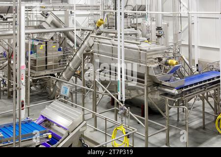 Maschinen, Schnecken, Öfen und Förderbänder aus rostfreiem Stahl, die zur Dehydrierung und Zubereitung von Lebensmitteln in einer sauberen, modernen Lebensmittelverarbeitungsanlage verwendet werden. Stockfoto