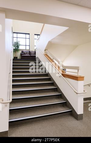 Rutschfeste Fußleisten und Sicherheitsgeländer auf den Stufen einer Gymnasialtreppe. Stockfoto