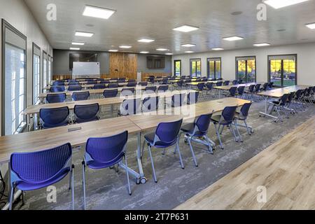 Tische und Stühle sind in Reihen in einem neuen modernen Schulungsraum in einem modernen Firmenbüro angeordnet. Stockfoto