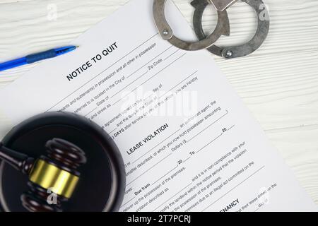 Hinweis zum Beenden oder zur Räumung: Leeres Dokumentenpapier, das mit Handschellen gefüllt werden kann, und Richter-Hammer auf dem Tisch in Nahaufnahme Stockfoto