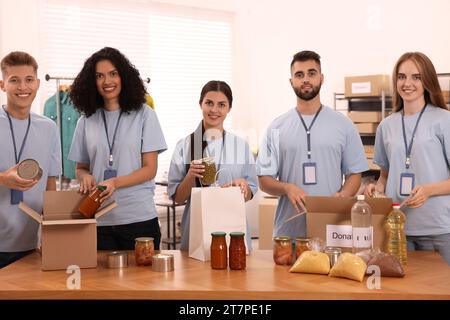 Porträt von Freiwilligen, die Lebensmittel am Tisch im Lager verpacken Stockfoto