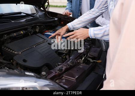 Fahrschule. Der Lehrer erklärt den Fahrzeugmotor für die Gruppe draußen, Nahaufnahme Stockfoto