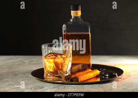 Tablett mit Whiskey, Zigarren und Cutter auf grauem Tisch Stockfoto