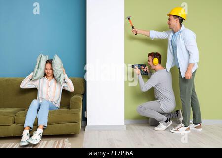 Junge Frau, die unter lauten Nachbarn leidet, die zu Hause renovieren Stockfoto