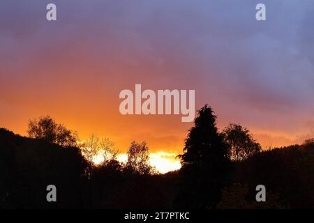 Sonnenuntergang mit dramitischen dunklen Wolken, Sonne scheint durch eine Lücke in den Wolken, roter Himmel, brennender Himmel, Silhouette, Rothaargebirge, Nordrhein-Westfalen Stockfoto