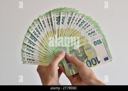 Eine Hand zählt viele hundert Euro-Banknoten, die wie ein Fächer aufgefächert werden und als Symbol für den Euro, Bargeld oder Reichtum dienen Stockfoto