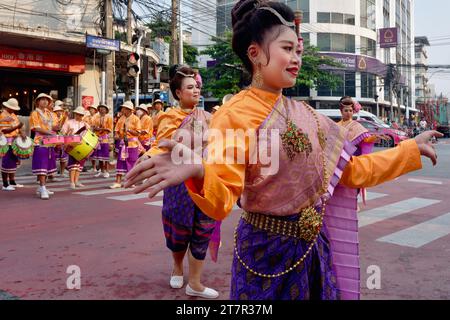 Während einer Feier in einem taoistisch-chinesischen Schrein in Bangkok, Thailand, tanzen Frauen in traditioneller thailändischer Kleidung anmutig auf der anderen Straßenseite Stockfoto