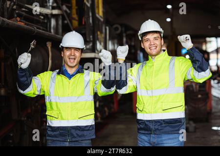 Glücklicher, fröhlicher Ingenieur männlicher Teammechaniker Mitarbeiter, der reflektierende Sicherheitskleidung mit Schutzhelm trägt, genießt das Lächeln zusammen Stockfoto