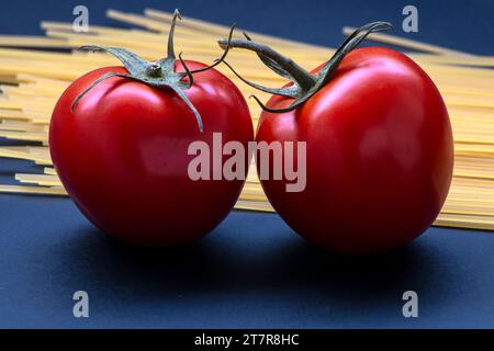 Realistisch aussehende Tomaten und rohe Nudeln isoliert auf blauem Hintergrund in Brasilien Stockfoto