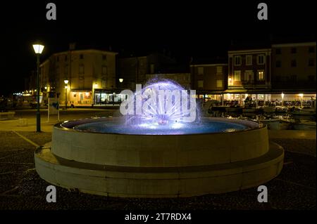 Cres, Kroatien - 8. April 2023: Detail eines Brunnens auf dem Hauptplatz in der Nähe des Hafens in Cres mit farbigen Lichtern Stockfoto