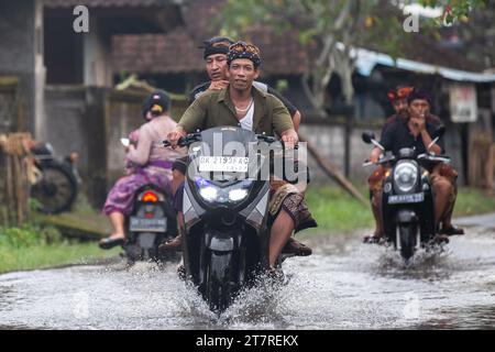 Sidemen, Bali, Indonesien - 24. März 2023: Unidentifizierte Personen pendeln durch eine überflutete Straße. Stockfoto