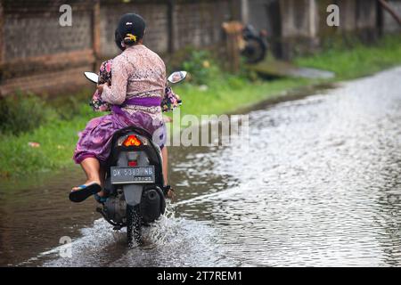 Sidemen, Bali, Indonesien - 24. März 2023: Unidentifizierte Personen pendeln durch eine überflutete Straße. Stockfoto