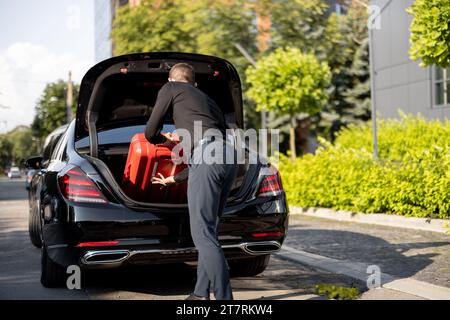 Chauffeur packt einen Koffer in ein Luxusauto Stockfoto