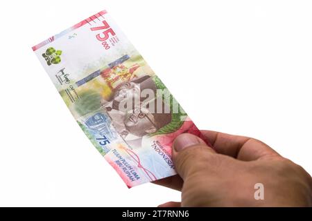 Die indonesische Rupiah ist die offizielle Währung Indonesiens. Die Hand eines asiatischen Mannes hält ein Stück Geld, um zu bezahlen. Business Income Investment Eco Stockfoto
