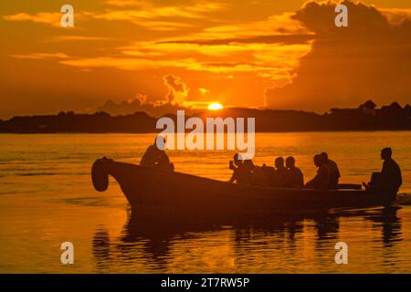 Silhoutte von Touristen auf einem Fischerboot bei Sonnenuntergang in Shela Beach, Old Town Lamu, UNESCO-Weltkulturerbe in Kenia Stockfoto