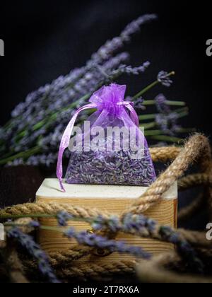 Eine kleine Tasche Lavendel auf einer Holzkiste mit einem Seil und Lavendelzweigen. Stockfoto
