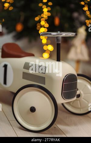 Ein Oldtimer-Rennwagen für Kleinkinder vor einem Weihnachtsbaum Stockfoto