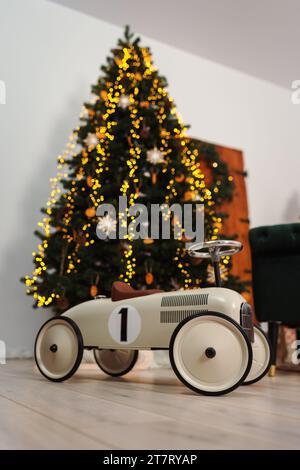 Ein Oldtimer-Rennwagen für Kleinkinder vor einem Weihnachtsbaum Stockfoto